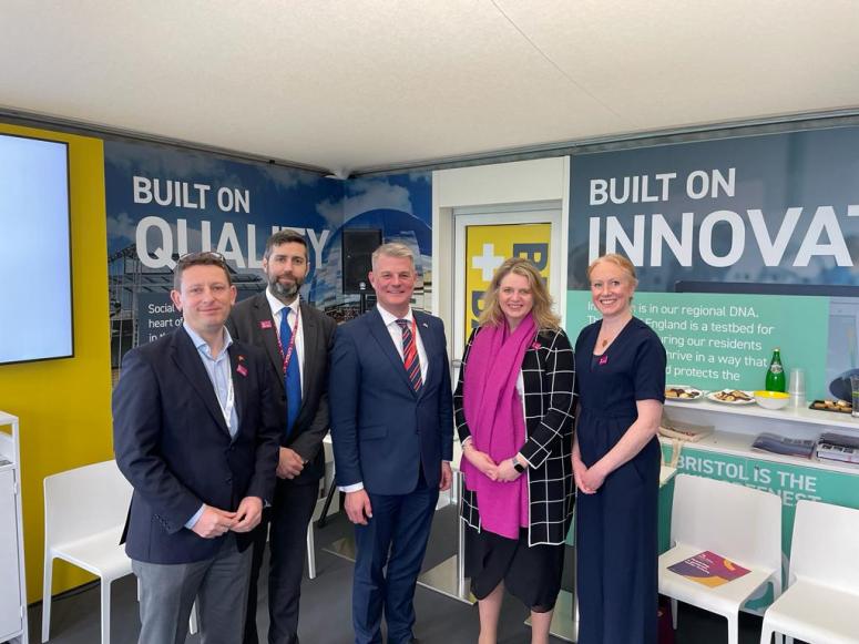 (from L to R) Richard Bonner, Councillor Toby Savage, Councillor Huw Thomas, Katherine Bennett and Jo Dally stand smiling in front of a corporate background with the phrases "built on quality" and "built on innovation" just visible. 